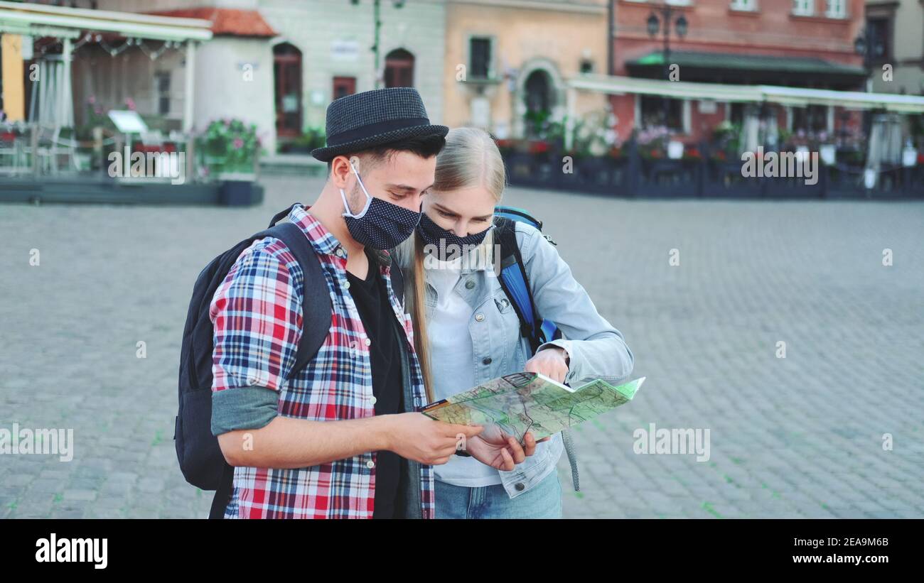 Zwei Touristen in Schutzmasken Überprüfung Karte auf zentralen Stadtplatz, dann bewundern einige schöne Stelle. Reisen während der Pandemie. Stockfoto