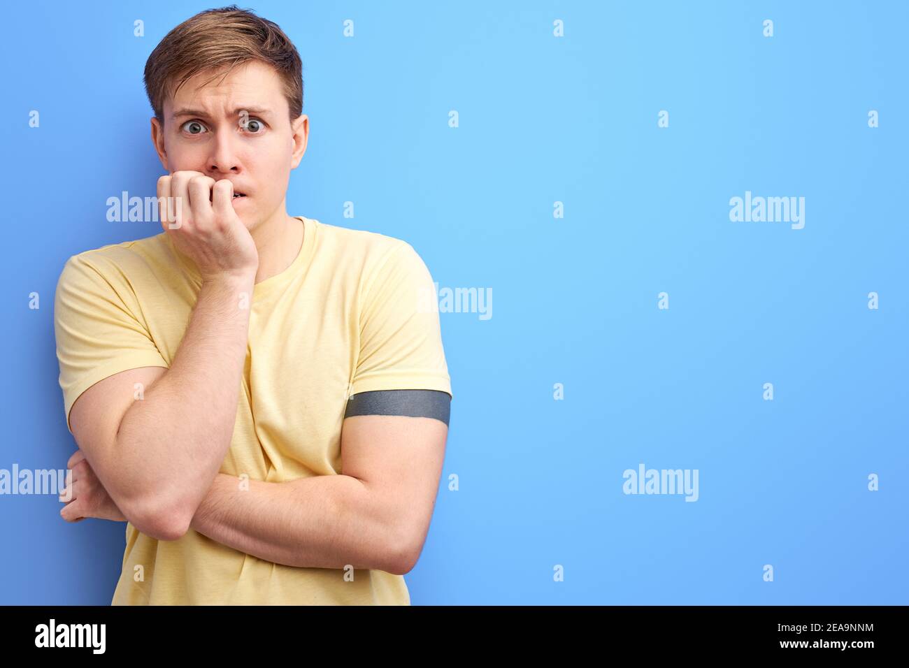 kaukasischen Kerl ist gestresst und nervös mit Händen auf Mund beißen Nägel. Angst Problem. Isolierte blauen Hintergrund Stockfoto