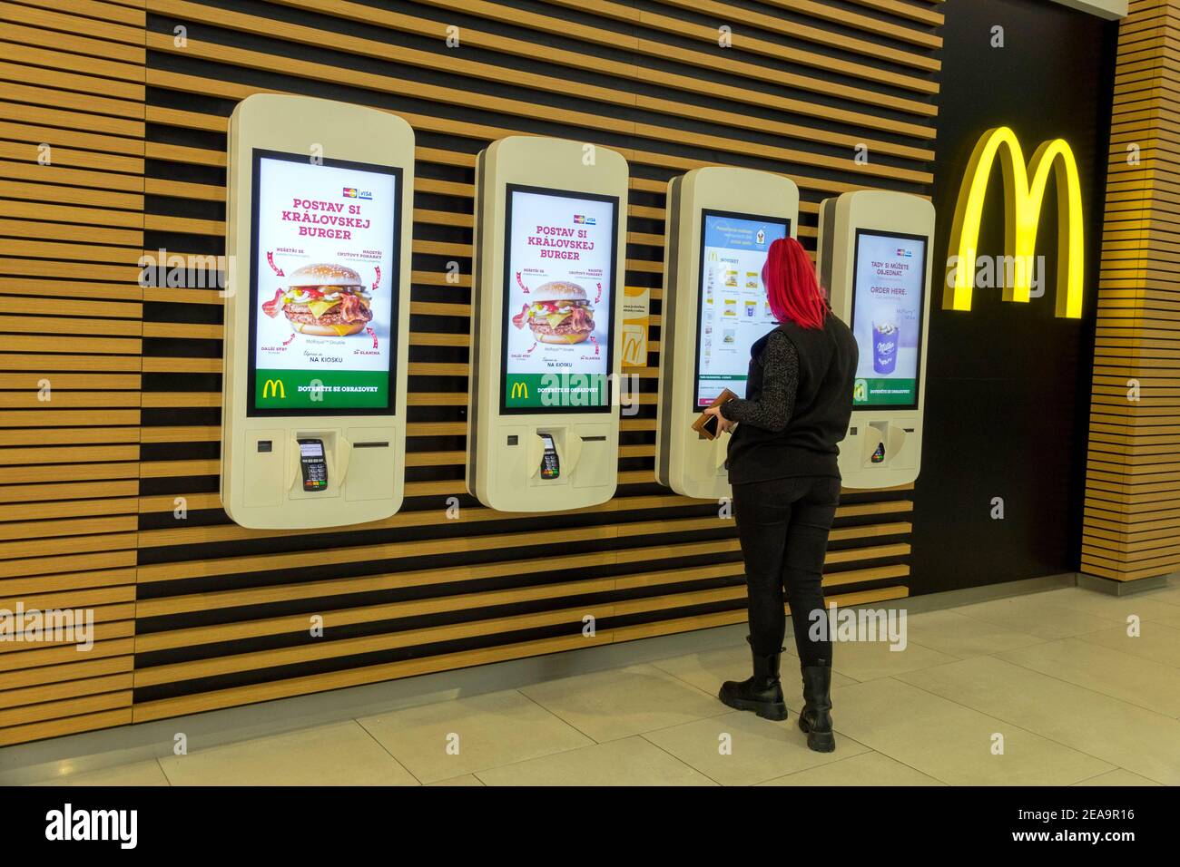 Eine junge Frau wählt ein Menü an einem Selbstbedienungskiosks mit Selbstbedienungsautomaten bei McDonalds in Tschechien Stockfoto