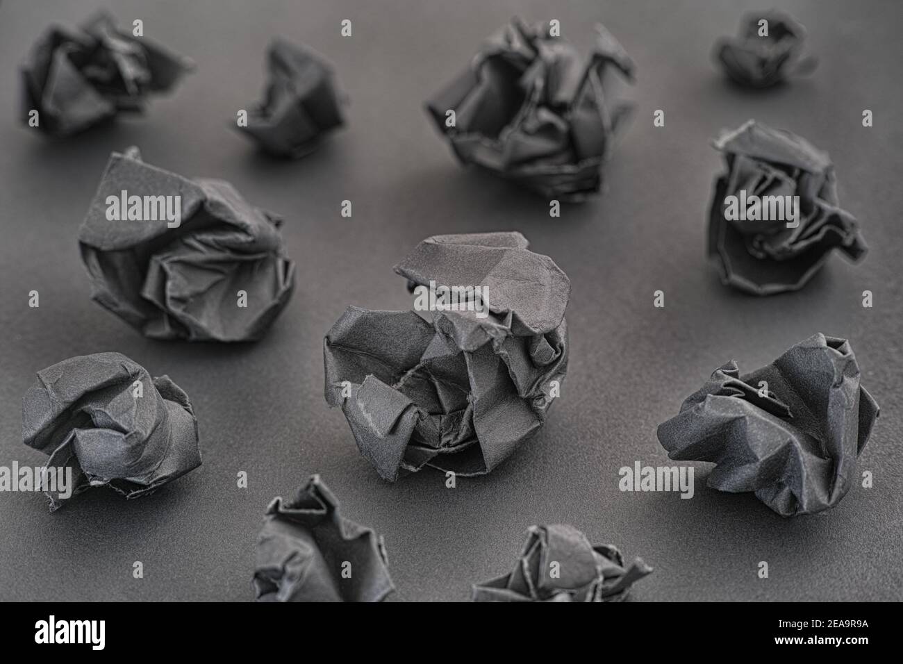 Zerknitterte schwarze Papierkugeln auf schwarzem Hintergrund. Ideenkonzept. Low-Taste. Nahaufnahme. Stockfoto