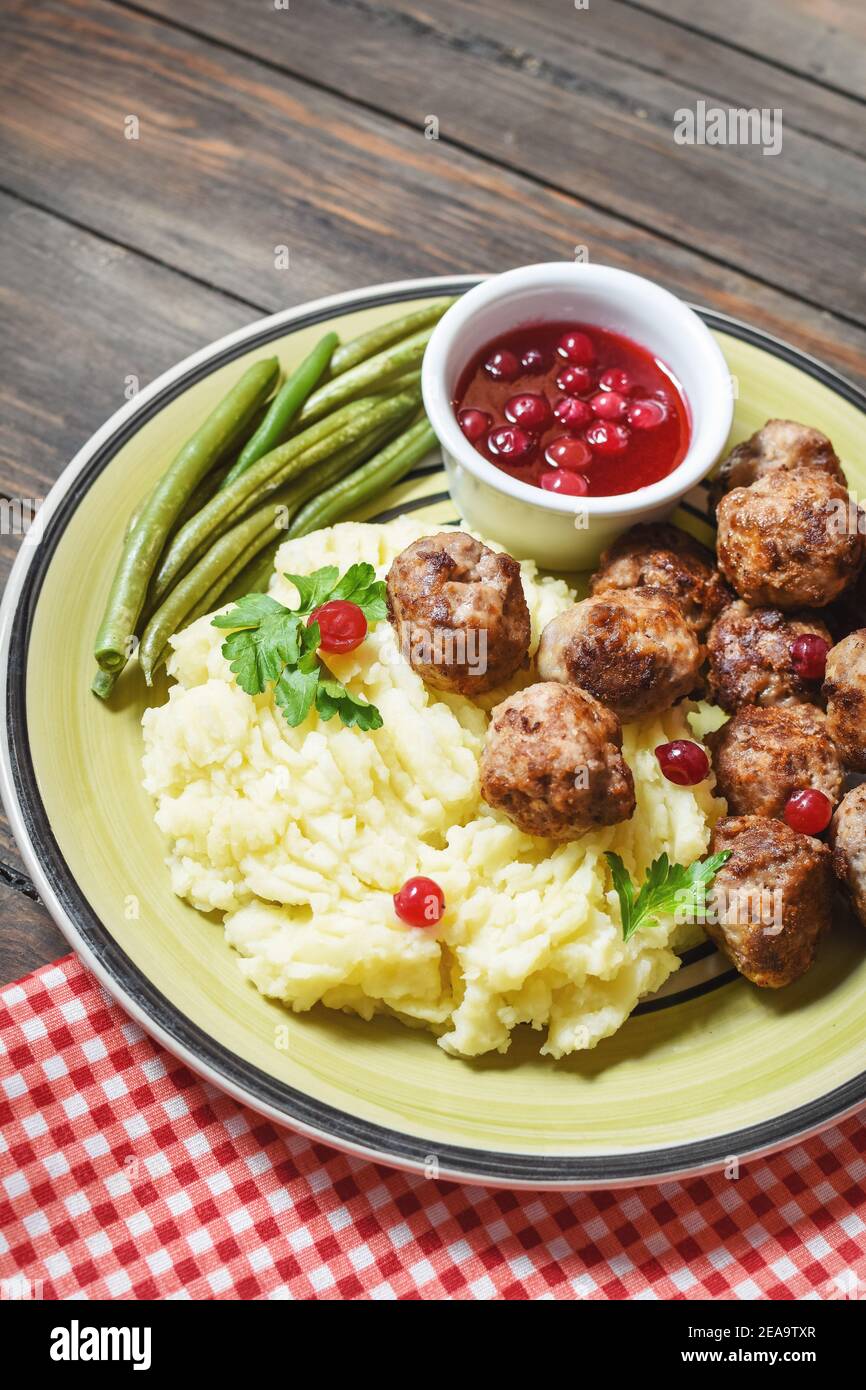 Schwedische Fleischbällchen mit Kartoffelpüree und grünen Bohnen auf Holzgrund. Stockfoto