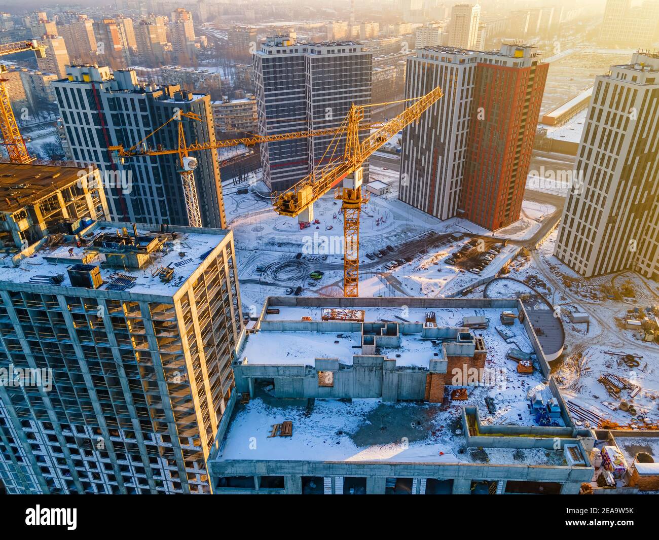 Baukran auf Baustelle umgeben von neuen Immobilien. Landschaftlich schöne Luftaufnahme von wachsenden Stadtvierteln Stockfoto