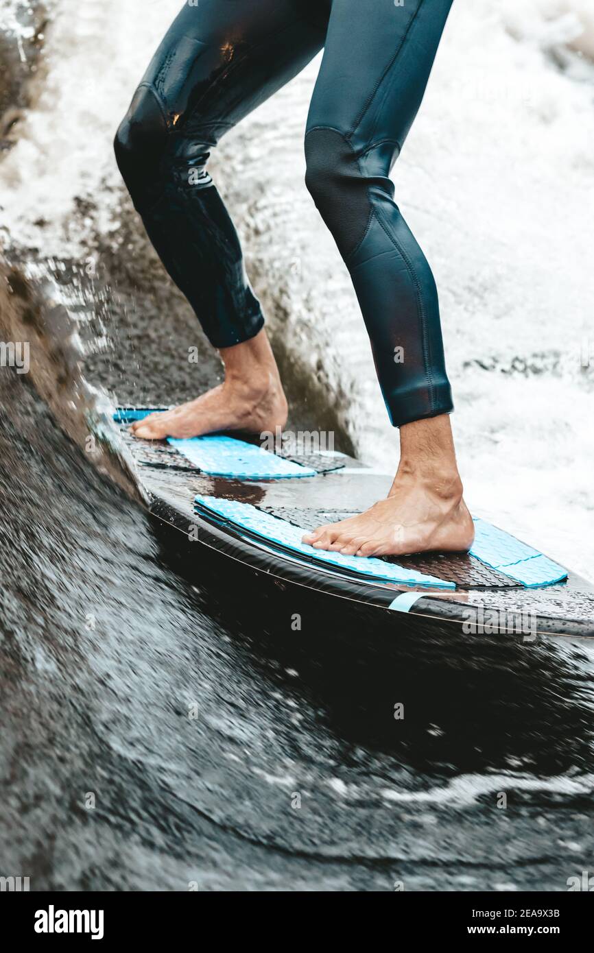 Unkenntlich fit kaukasischen Mann reitet wecken Brandung auf Fluss oder See am Abend in der untergehenden Sonne. Konzept für Wassersport, Wochenendaktivitäten. Vorderansicht. Stockfoto