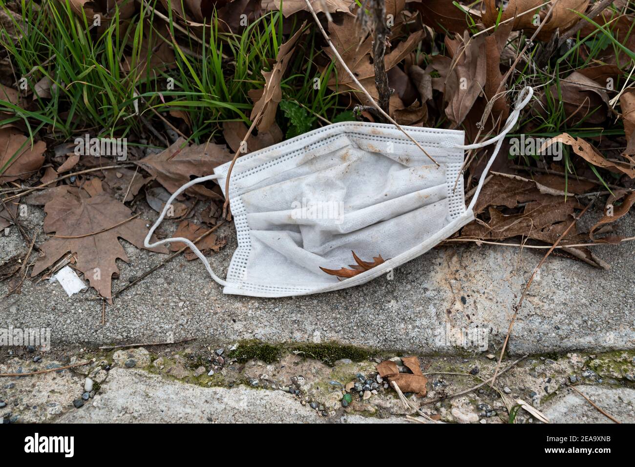 Maske für den medizinischen Schutz verloren auf dem Boden. Einwegmaske liegt auf der Straße. Falsche Entsorgung der Gesichtsmaske. Stockfoto