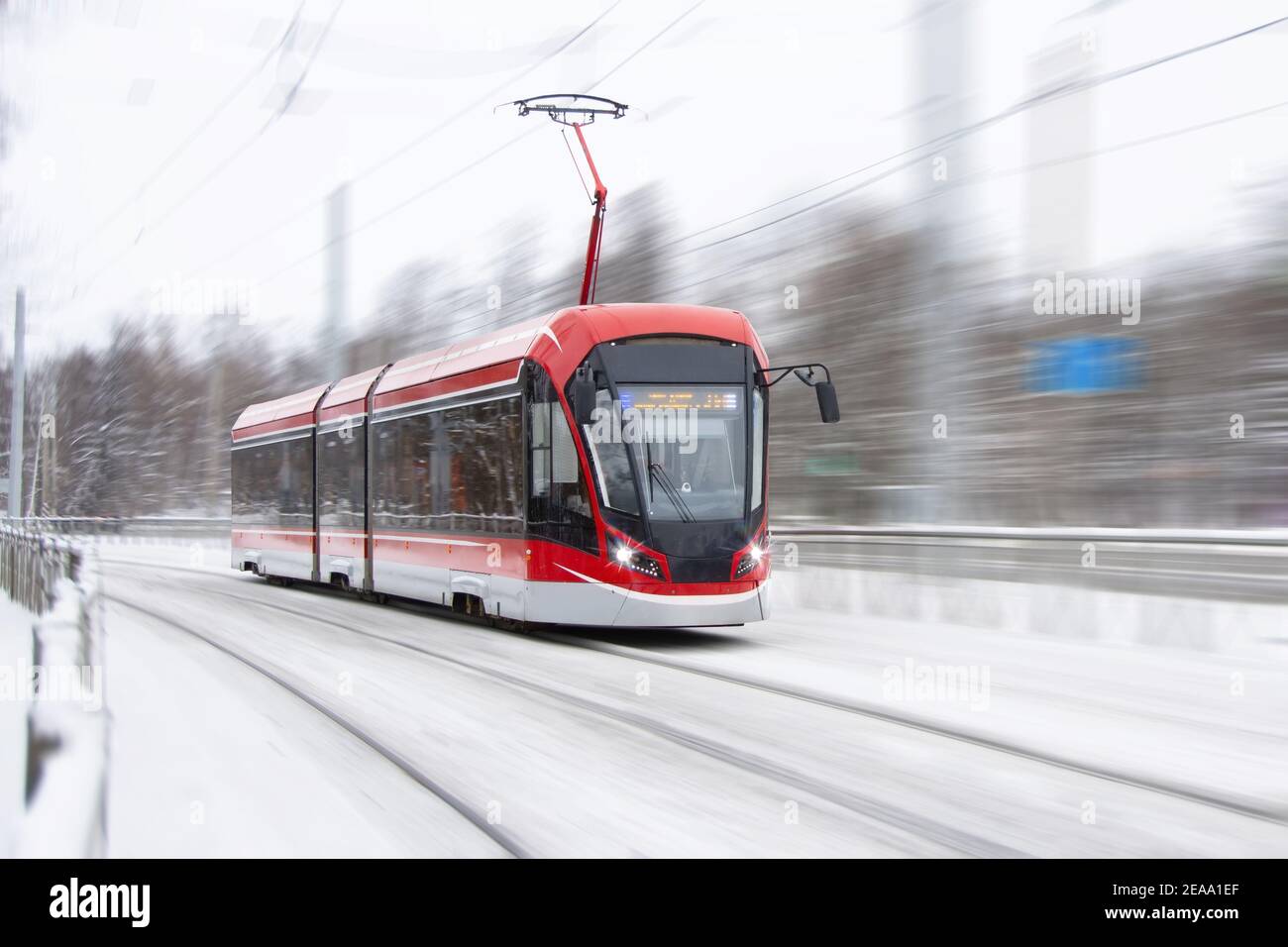 Die Straßenbahn fährt schnell an einer Kurve in A vorbei Schneebedeckter Stadtpark Stockfoto