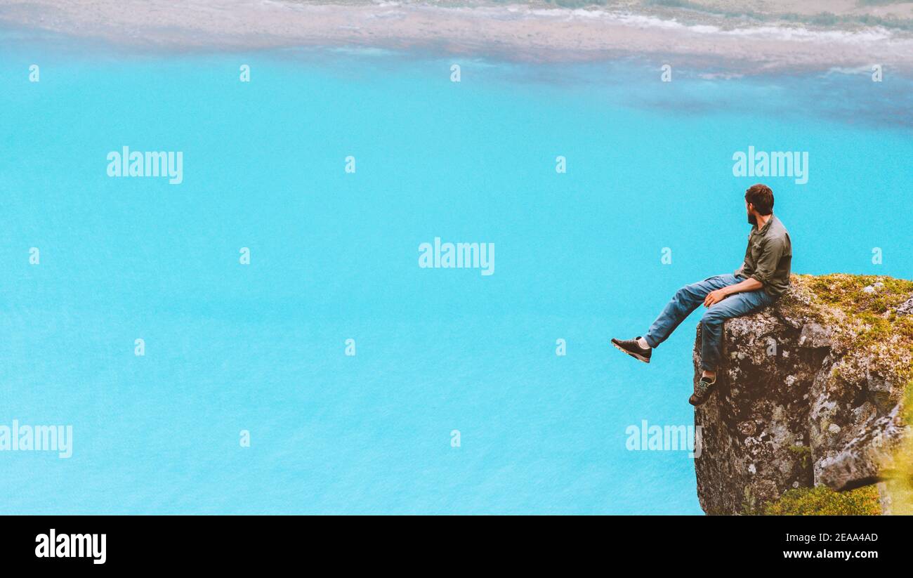 Mann sitzt auf Klippe Kante reisen allein Blick auf Antenne Blue Sea View in Norwegen Wandern solo Outdoor gesunde Lebensweise Sommerurlaub Stockfoto