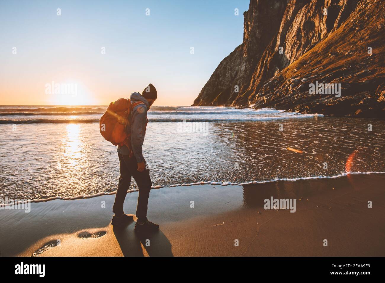 Mann unterwegs Wandern mit Rucksack am Sandstrand Sonnenuntergang Ozean Sehen Sie Abenteuer Lifestyle Aktivurlaub Outdoor-Solo-Reise in Norwegen Stockfoto