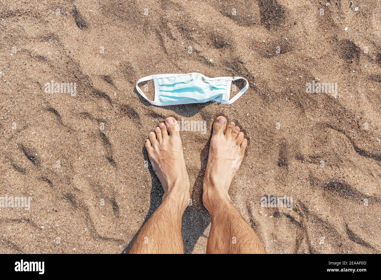 Gebrauchte medizinische Maske auf einem Sandstrand am Meer entsorgt. Das Konzept von unverantwortlichem Verhalten und Umweltverschmutzung. Ein weiteres soziales Problem Stockfoto