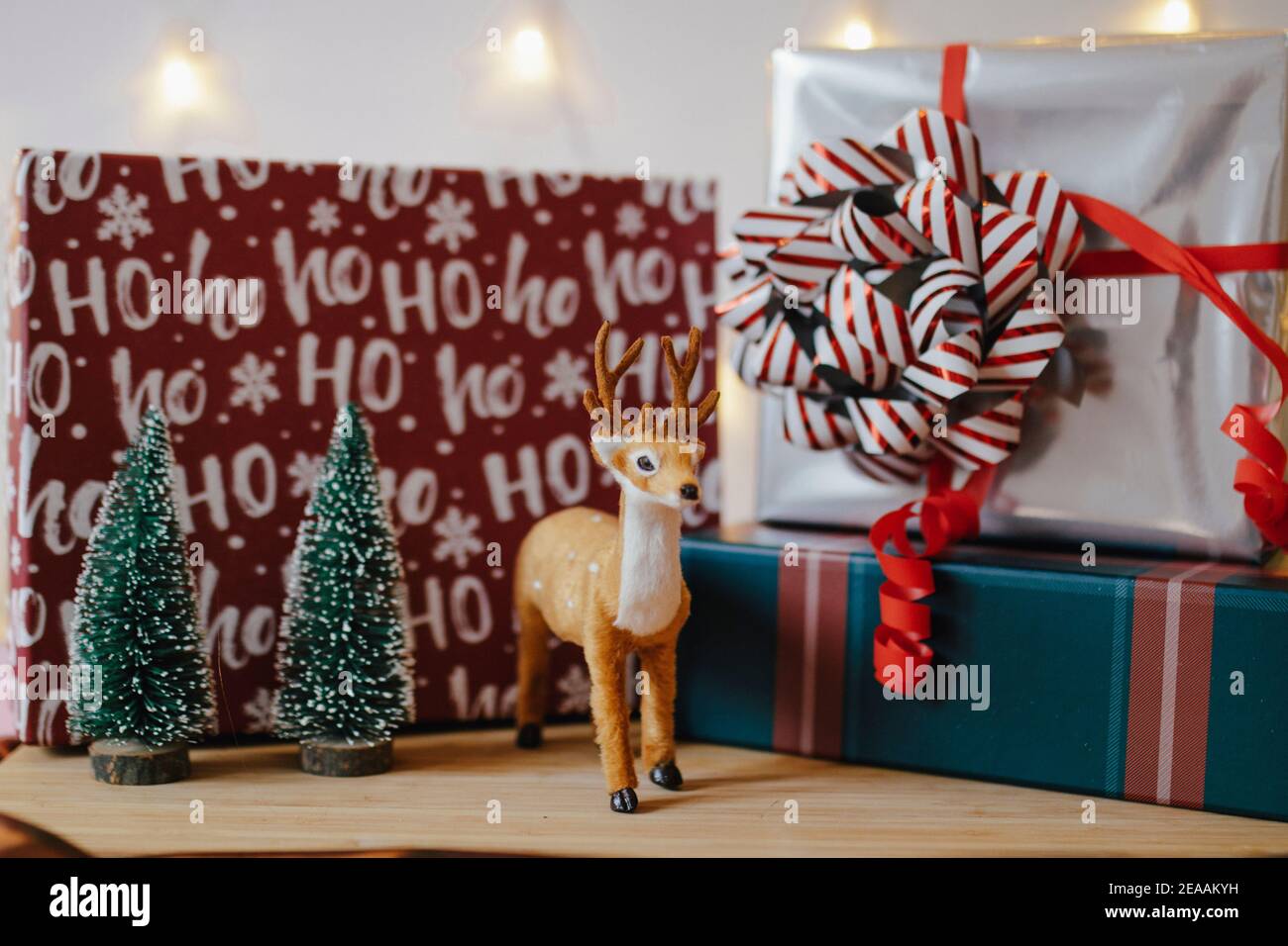 Weihnachtsdekoration mit Geschenken in Schachteln, kleinen Tannen und Hirschen vor einem Lichtvorhang, romantische Stimmung Stockfoto