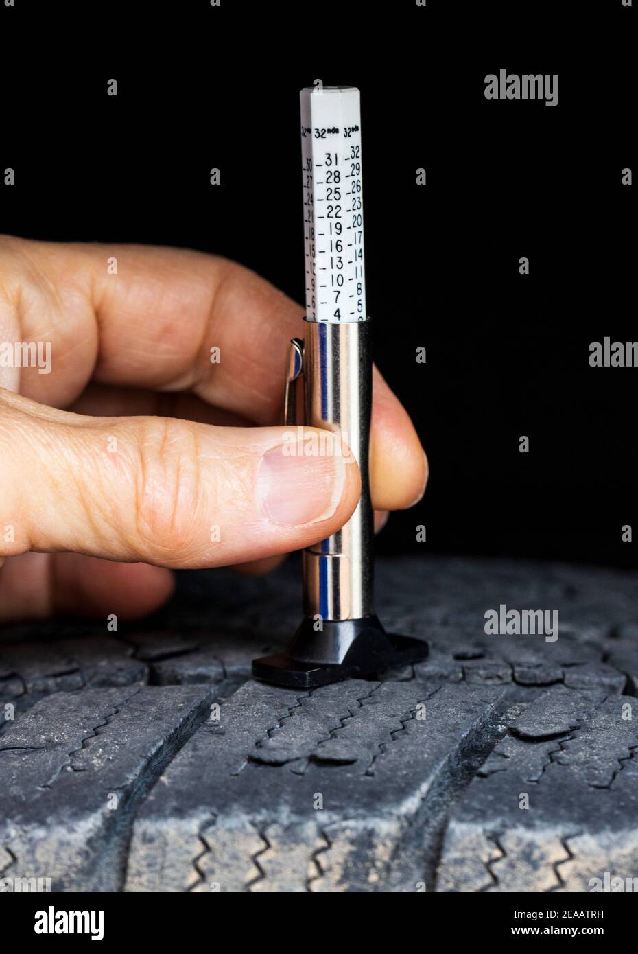 Messen des Reifenprofilverschleißes; Hand halten eines Reifentiefenmessers auf einem Michelin-Reifen Stockfoto