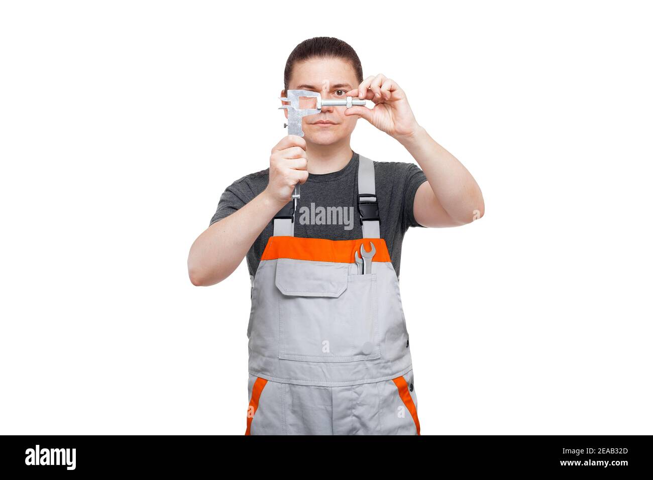 Mechaniker in Uniform hält Bolzen mit Mutter und Messschieber In der Tasche mit Schraubenschlüssel nimmt Kontrolle Messung Größe von Stahl Eisen Teil mit Gewinde fo Stockfoto