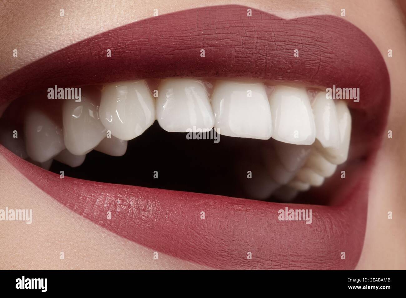 Breites Lächeln der jungen schönen Frau mit perfekten gesunden weißen Zähnen auf grauem Hintergrund. Zahnaufhellung, ortodont, Pflege Zahn und Wellness. Rote Lippen Stockfoto