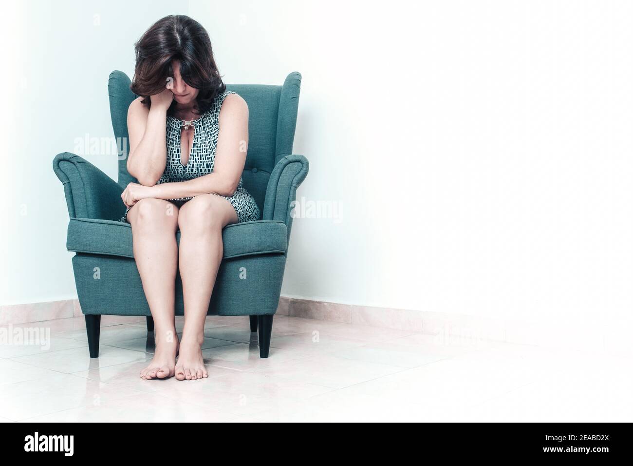 Gestresste und traurige Frau, die allein auf einem Stuhl sitzt - Mit Platz für Text Stockfoto