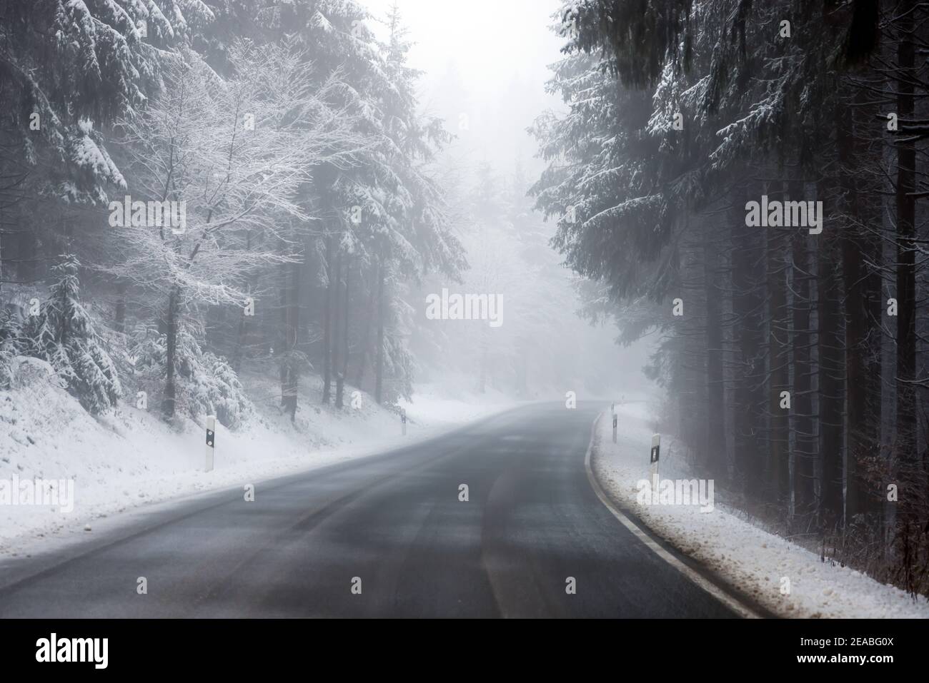 Winterberg, Sauerland, Nordrhein-Westfalen, Deutschland - verschneite Landschaft im Wald mit einer leeren Landstraße. Stockfoto