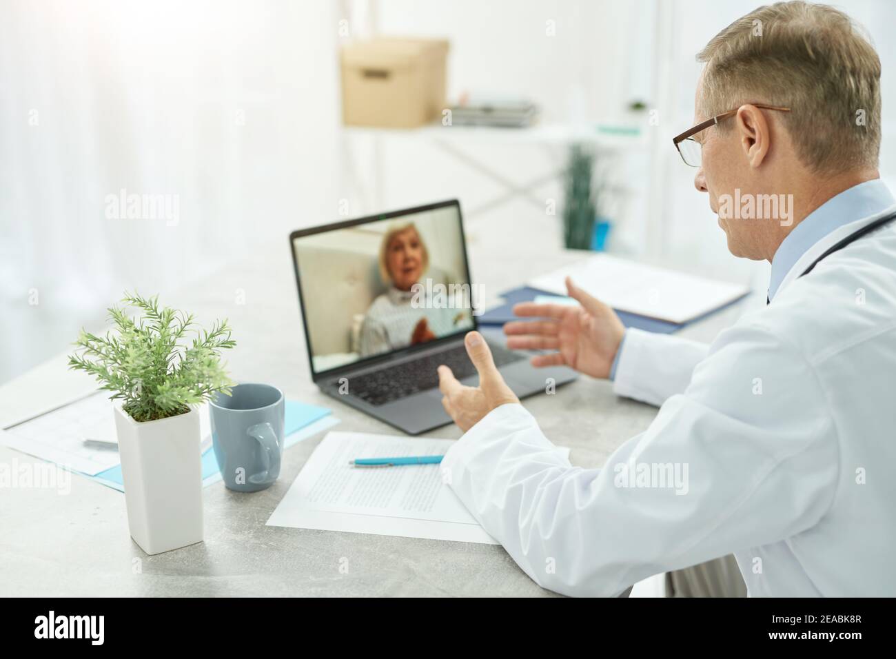 Männlicher Arzt bietet Online-Beratung für alte Frau in der Klinik Stockfoto