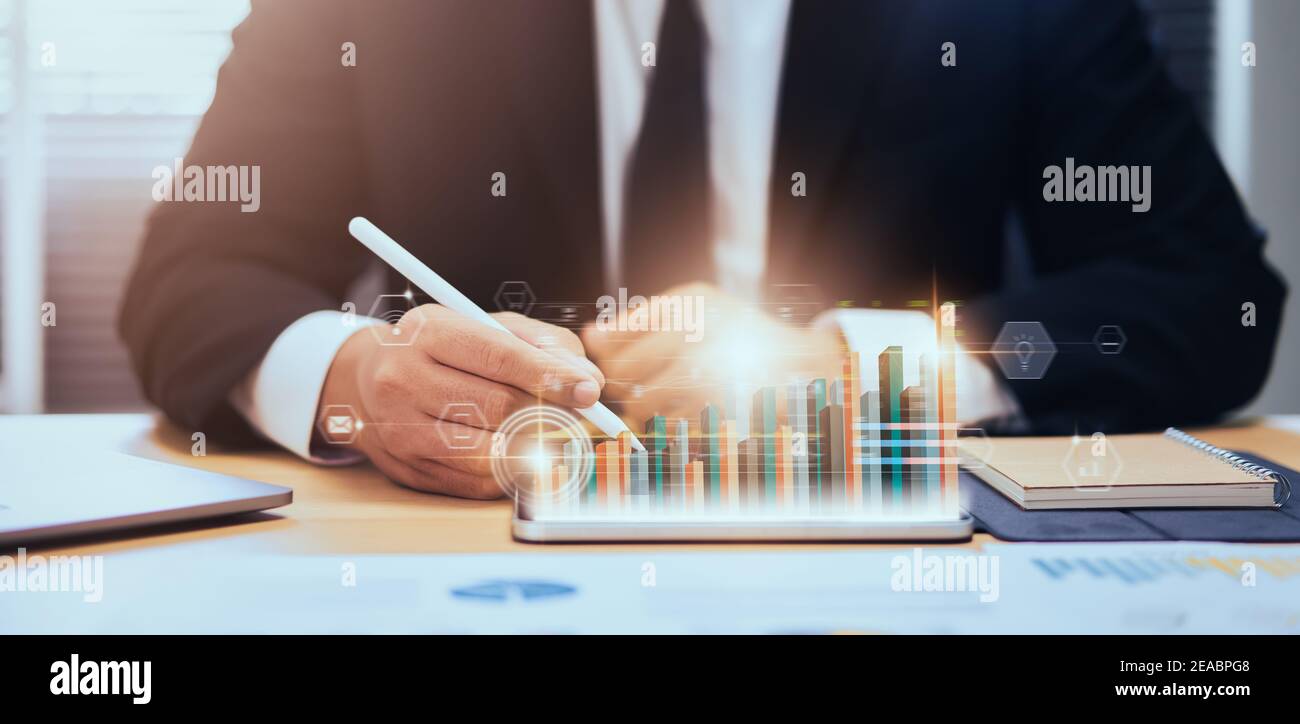 Börsenmarktkonzept, Geschäftsmann Hand Händler drücken digitale Tablette mit Grafiken Analyse Kerze Linie auf dem Tisch im Büro, Diagramme auf dem Bildschirm. Stockfoto