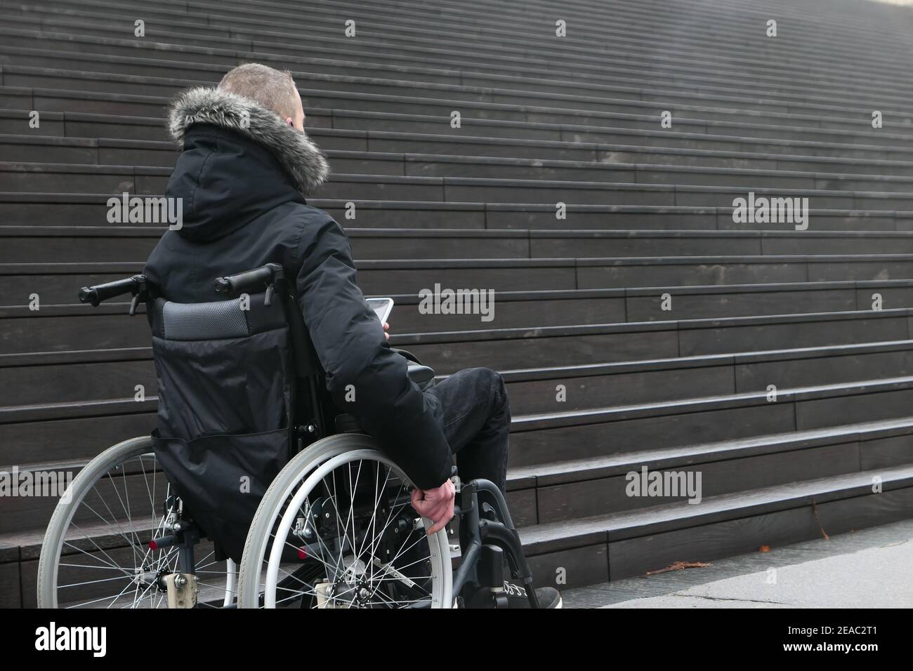 Konzept der behinderten Person. Mann im Rollstuhl draußen auf der Straße vor der Treppe. Stockfoto