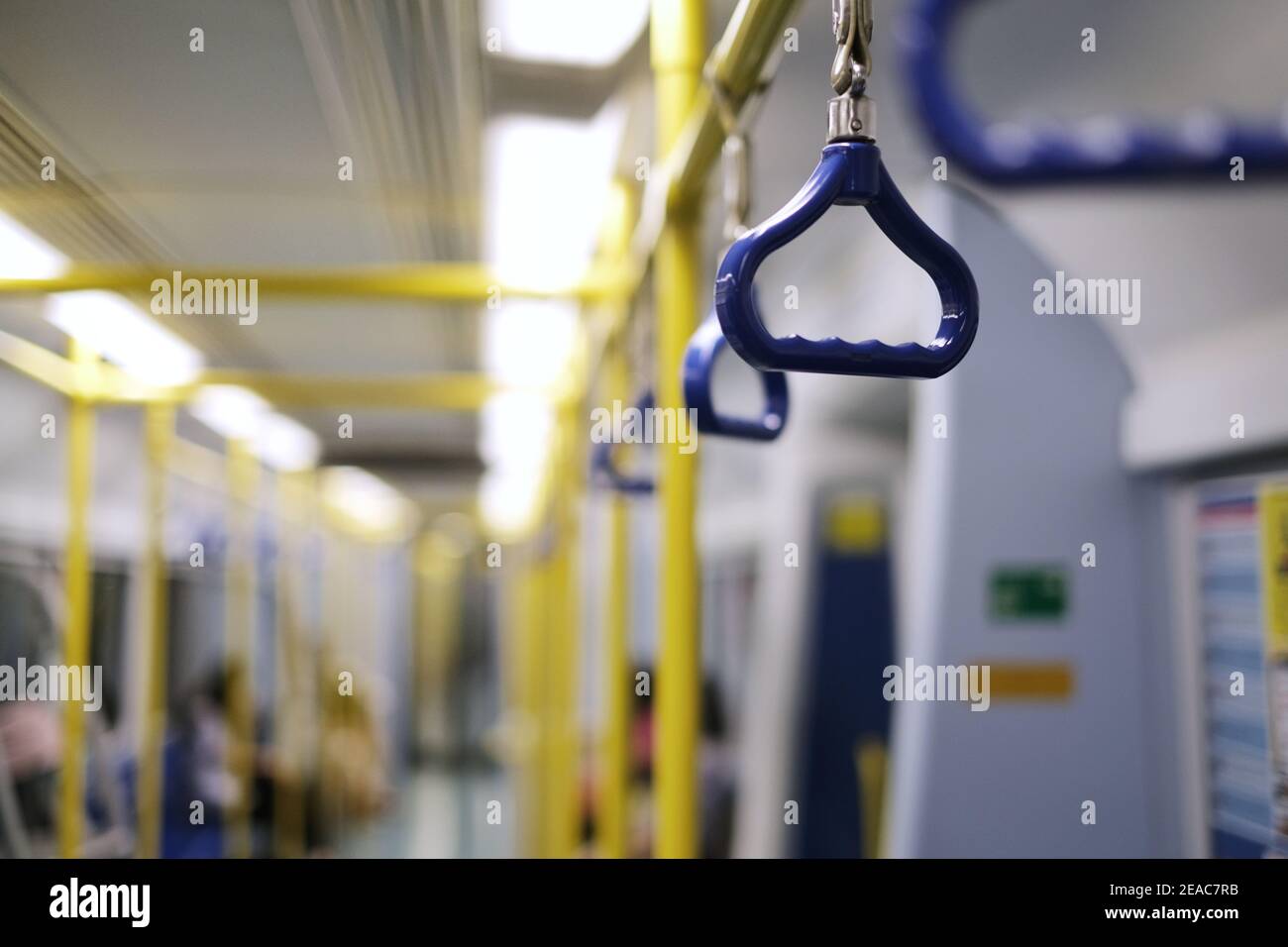 Reihen von blauen Handläufen und leuchtend gelben Metallstangen auf einem Hochgeschwindigkeitszug für Stabilität und Sicherheit der Passagiere. Stockfoto