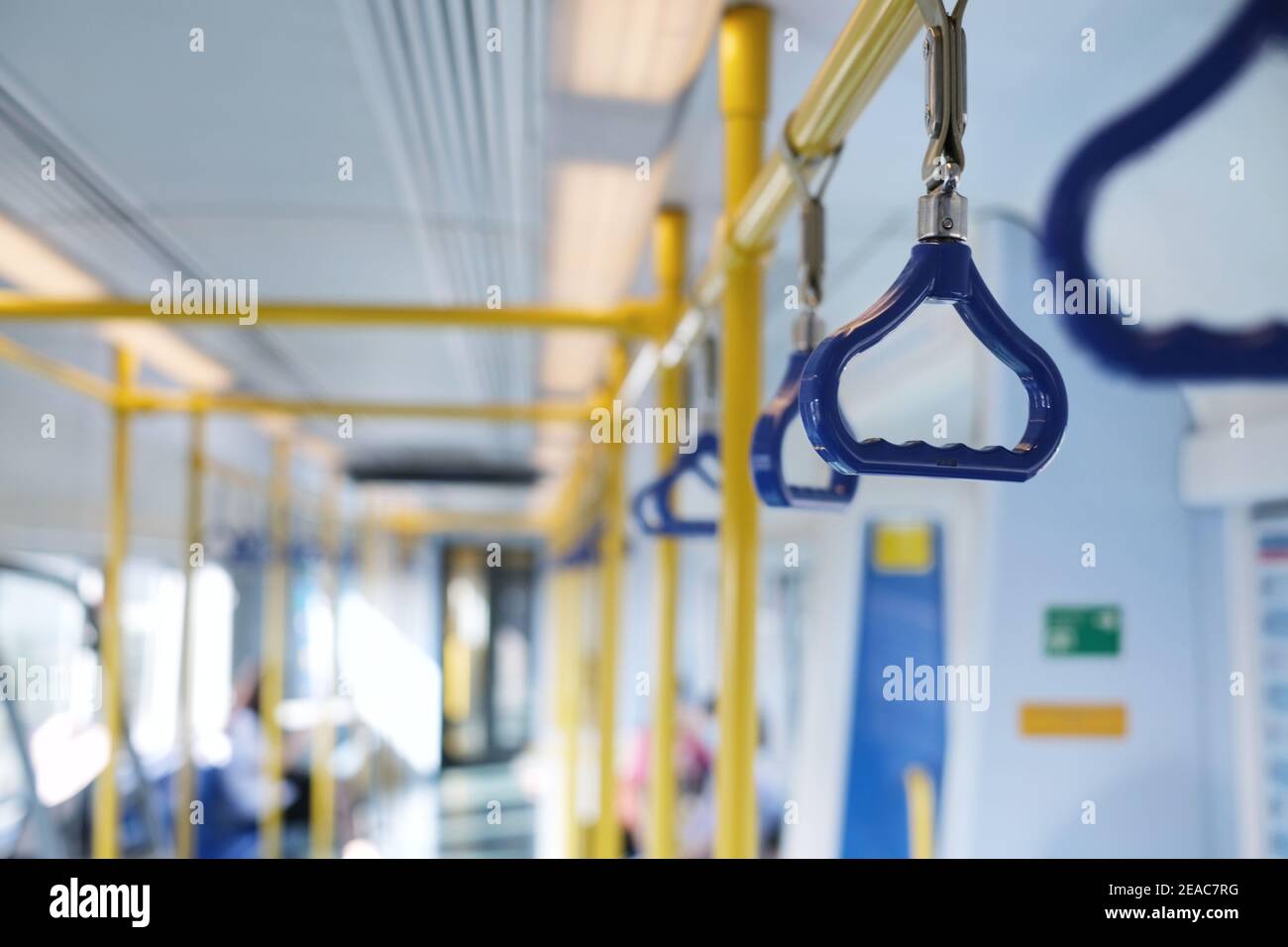 Reihen von blauen Handläufen und leuchtend gelben Metallstangen auf einem Hochgeschwindigkeitszug für Stabilität und Sicherheit der Passagiere. Stockfoto