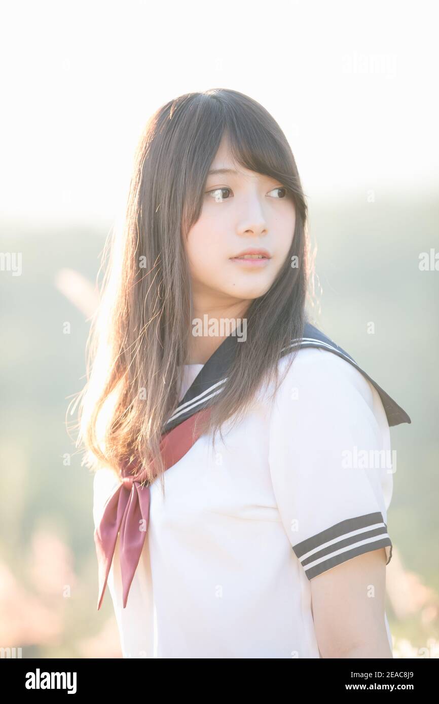 Portrait der asiatischen japanischen Schule Mädchen Kostüm Blick auf Park Im Freien bei Sonnenuntergang Stockfoto