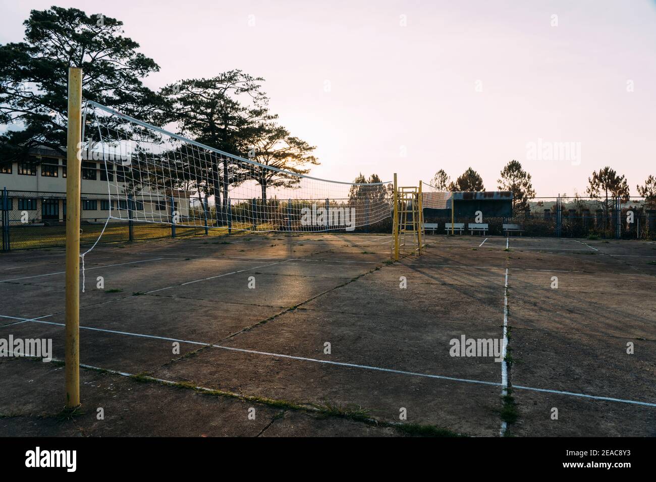 Alte, zerschlagte Zement-Volleyballplätze mit gelben Stöcken bei Sonnenuntergang in Dalat, Vietnam. Stockfoto