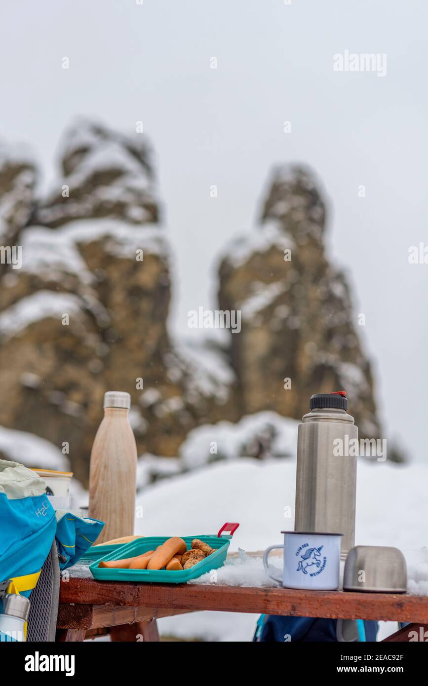 Picknick im Winter liegen Würste auf einem Tisch in einer Tupperware-Box. Daneben befinden sich Thermoskannen. Stockfoto