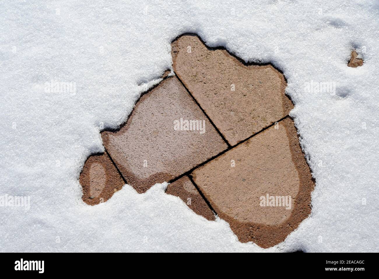 Schnee schmilzt auf Steinplatten Stockfoto