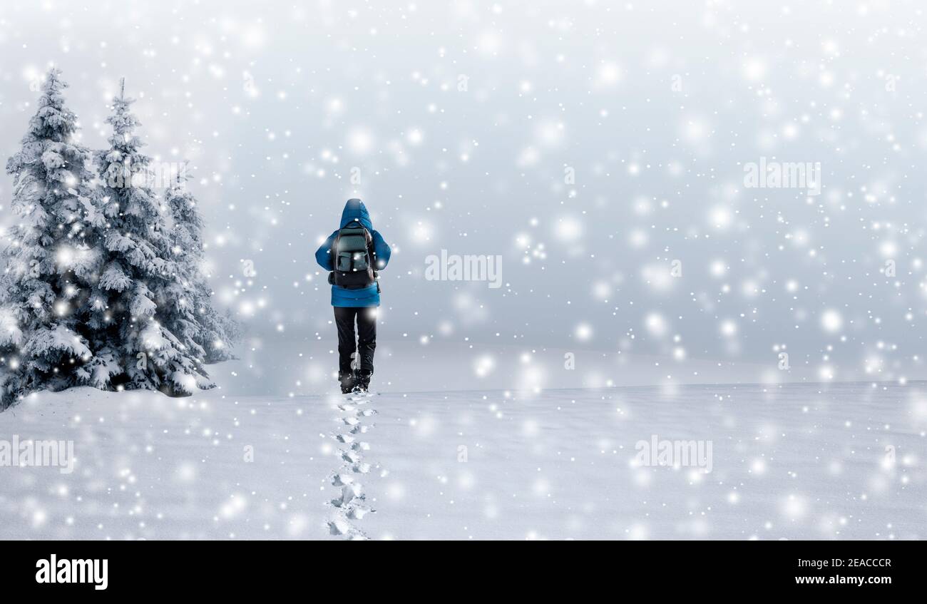 Person in blauer Jacke geht im Schnee Stockfoto