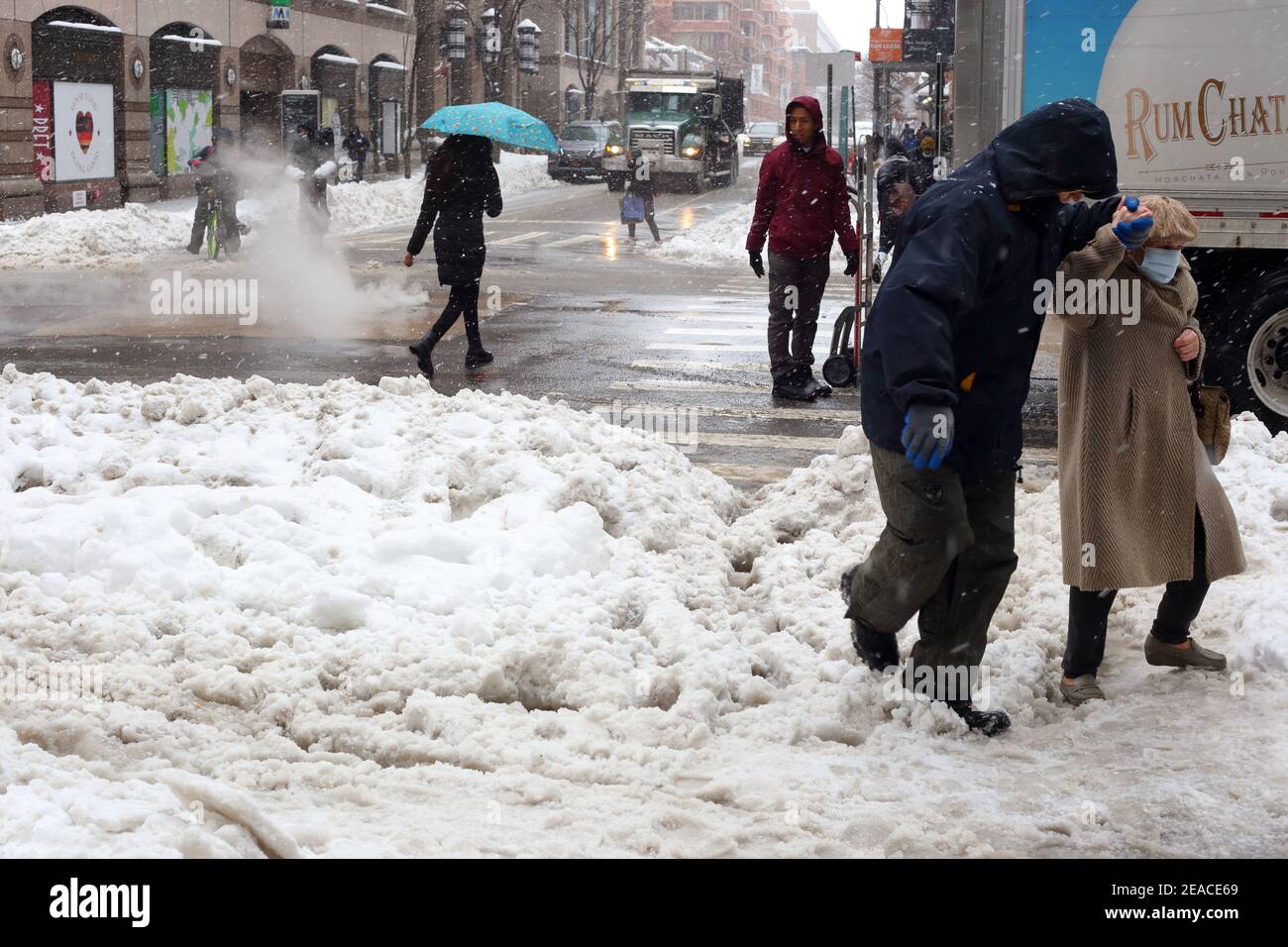 Die Menschen behutsam - und die älteren Menschen, gefährlich - navigieren durch ungeklärten Schnee und Slush auf einer Straßenecke in New York City nach einem Winter Schneesturm. Stockfoto