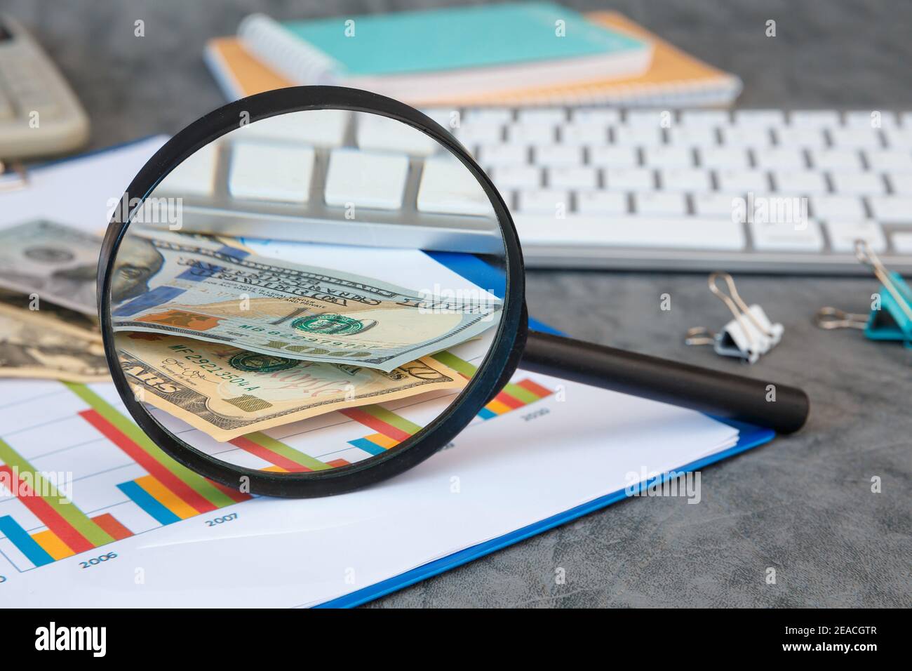 Lupe und Büromaterial, Geld, Dokumente, Tastatur auf grauem Hintergrund. Stockfoto