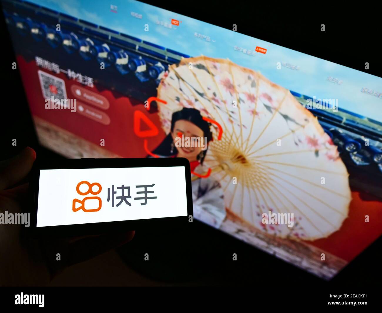 Person hält Smartphone mit Logo der chinesischen Video-Sharing-App-Entwicklung Unternehmen Kuaishou auf dem Bildschirm vor der Website. Konzentrieren Sie sich auf die Telefonanzeige. Stockfoto