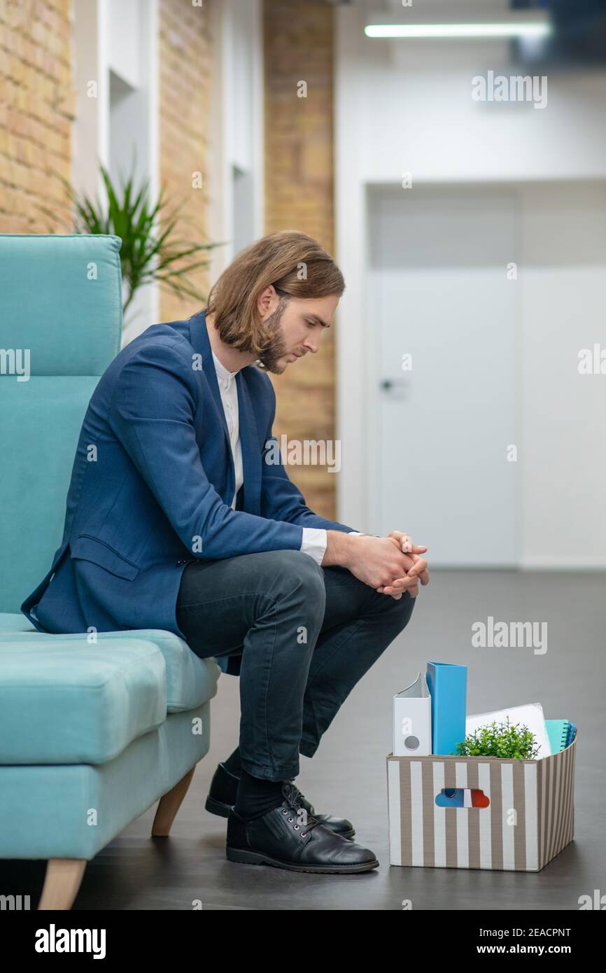 Trauriger Mann Büroangestellter sitzt im Flur Stockfoto