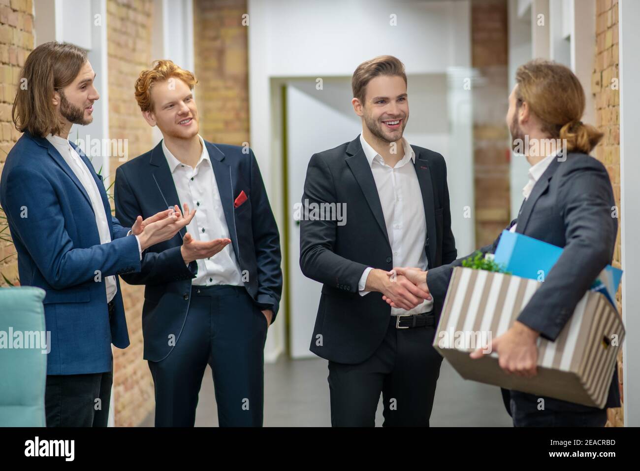 Mann mit Box und drei gratulierenden Kollegen Stockfoto