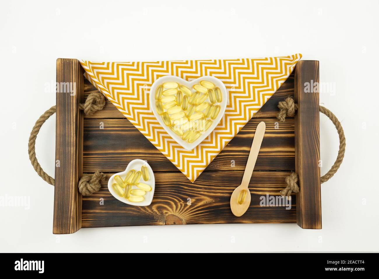 Gelbe Kapseln von Omega 3 liegen auf weißen Keramikplatten In Form der Herzen Stockfoto