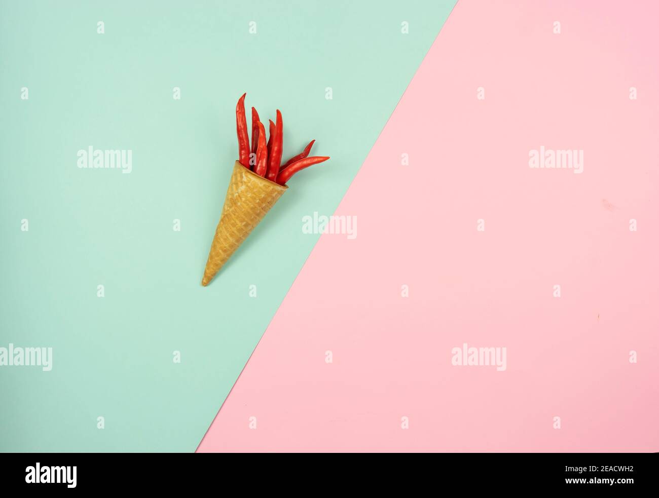 Ein Waffelkegel mit einem Bund roter Chili-Paprika darin iles auf einem bunten Hintergrund. Speicherplatz kopieren Stockfoto