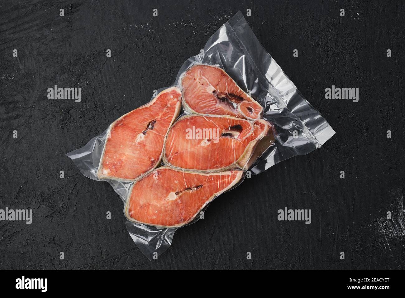 Overhead Ansicht von rohem Lachssteak in Vakuumverpackung auf Dunkler Hintergrund Stockfoto