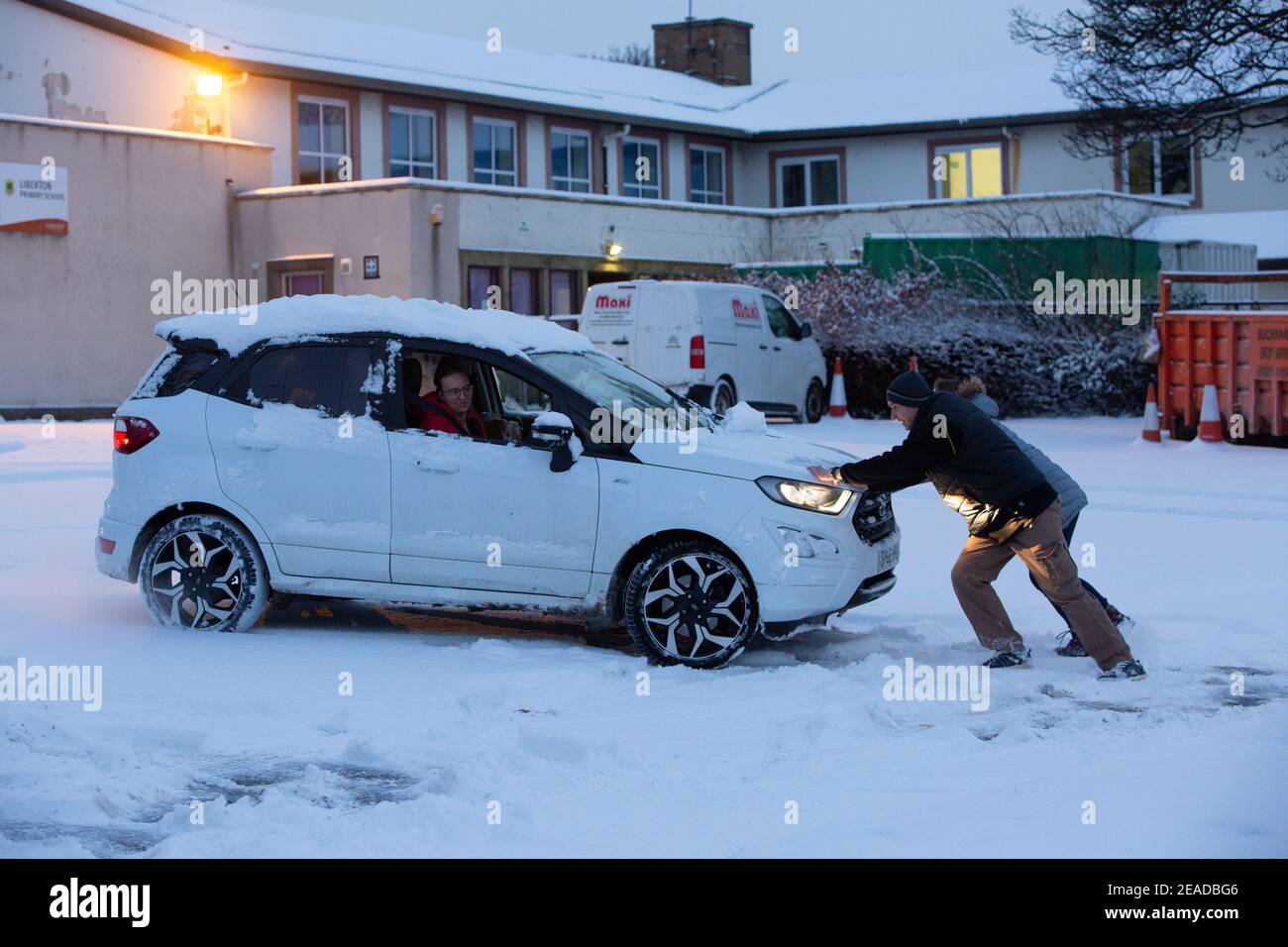 Edinburgh, Großbritannien. Februar 2021, 9th. Storm Darcy trifft Schottland im Südosten von Edinburgh. Der Zoll. Im Bild: Mitglieder der Öffentlichkeit schieben ein Auto auf den Parkplatz des Inchview Care Home. Quelle: Pako Mera/Alamy Live News Stockfoto