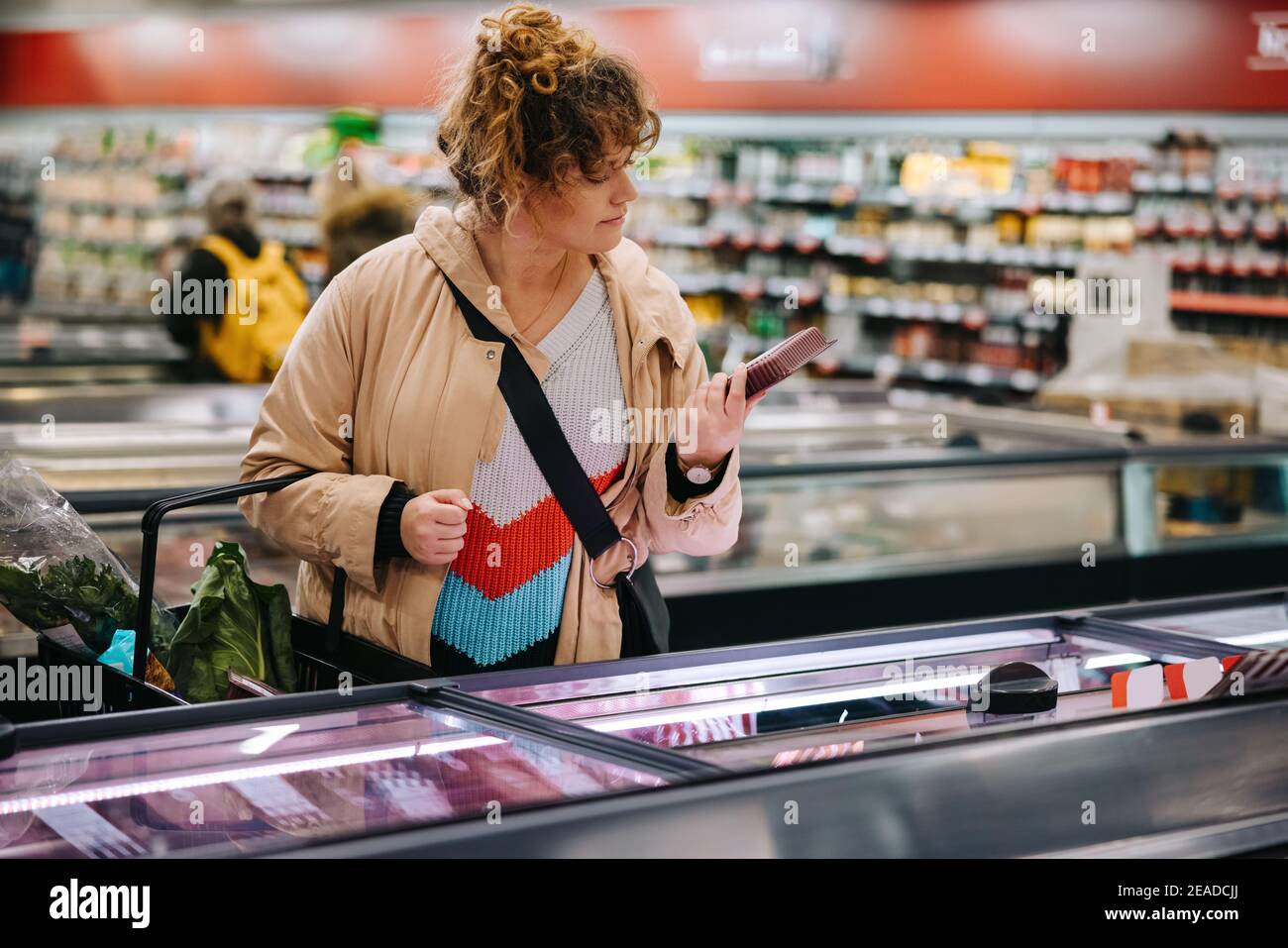 Frau im Lebensmittelgeschäft beim Lesen von Lebensmitteletiketten. Weibliche Kundin beim Lesen der Produktinformationen im Supermarkt. Stockfoto