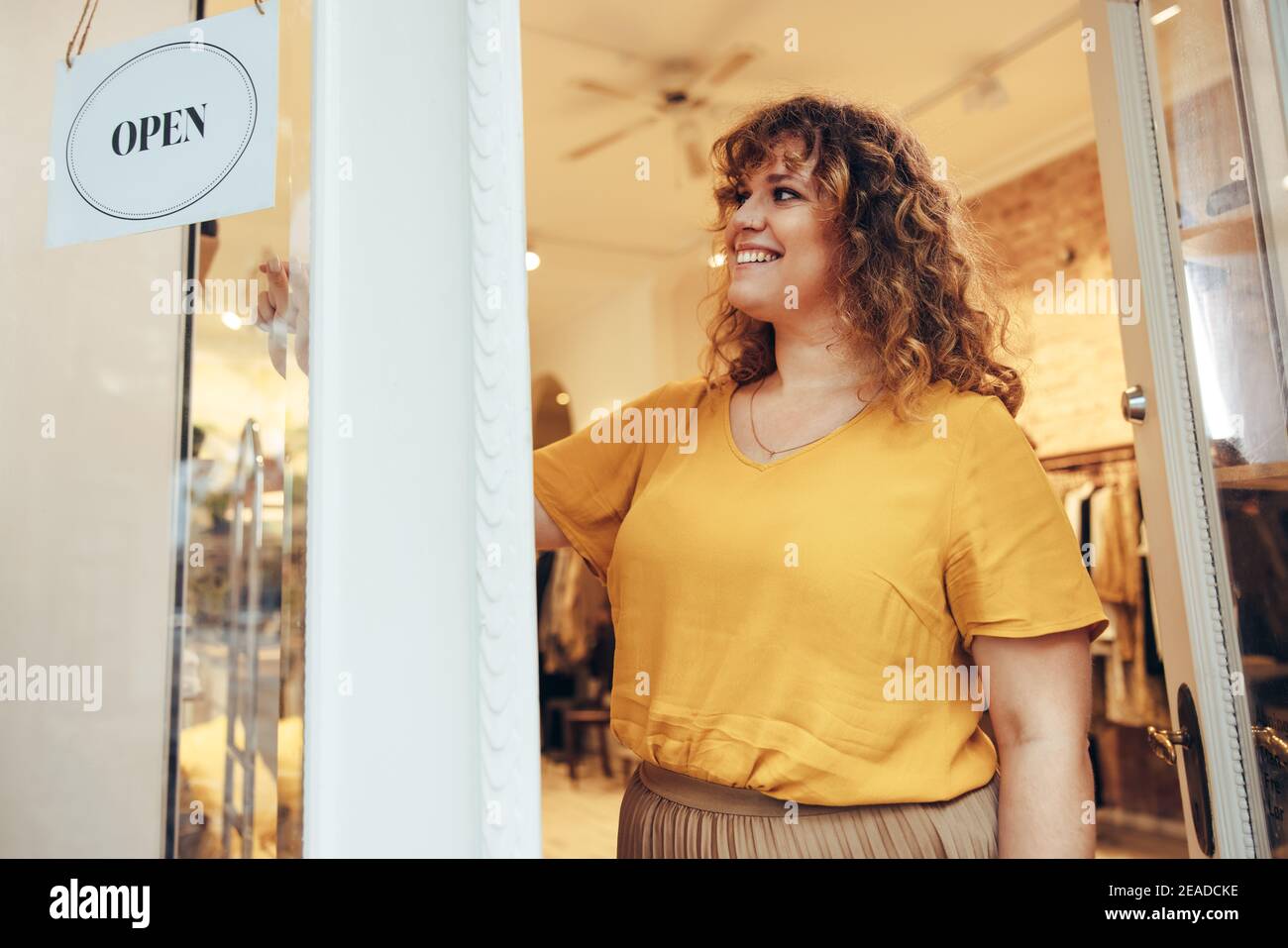 Inhaber eines kleinen Unternehmens, der das Türschild aufdrehte, um es zu öffnen. Die Inhaberin der Modeboutique eröffnet ihr Geschäft für Geschäfte. Stockfoto