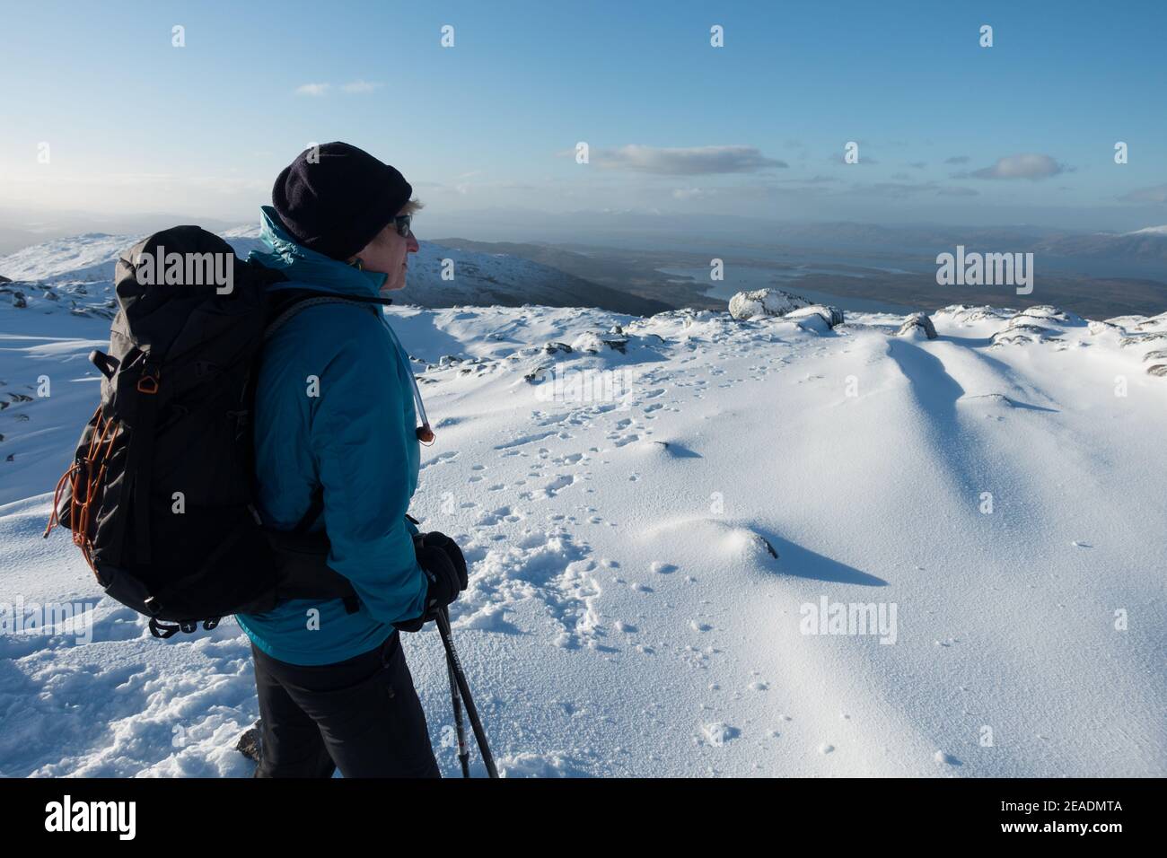 Eine Frau genießt eine Pause und die Aussicht beim Gehen In den schneebedeckten Bergen Schottlands Stockfoto