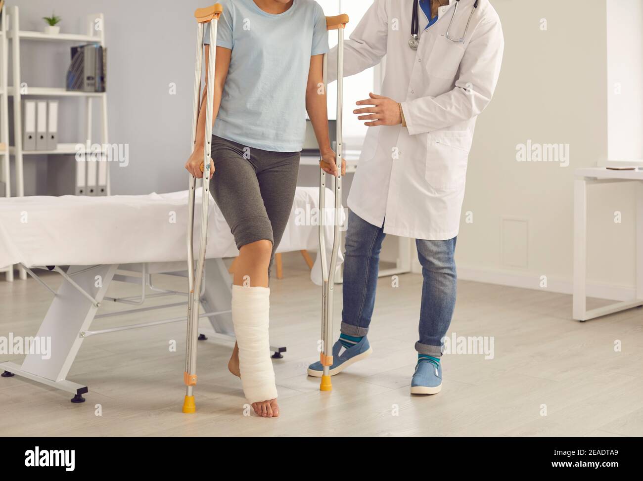 Patient mit gebrochenem Bein beim Gehen mit Krücken, die vom Arzt  unterstützt werden Während des Krankenhausaufenthalts Stockfotografie -  Alamy