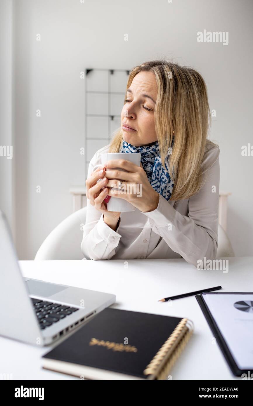 Kranke kaukasische Frau im Büro fühlen sich unwohl sitzen vor ihrem Laptop, gestresste weibliche Mitarbeiter haben Angst Angriff am Arbeitsplatz trinken Tasse Stockfoto