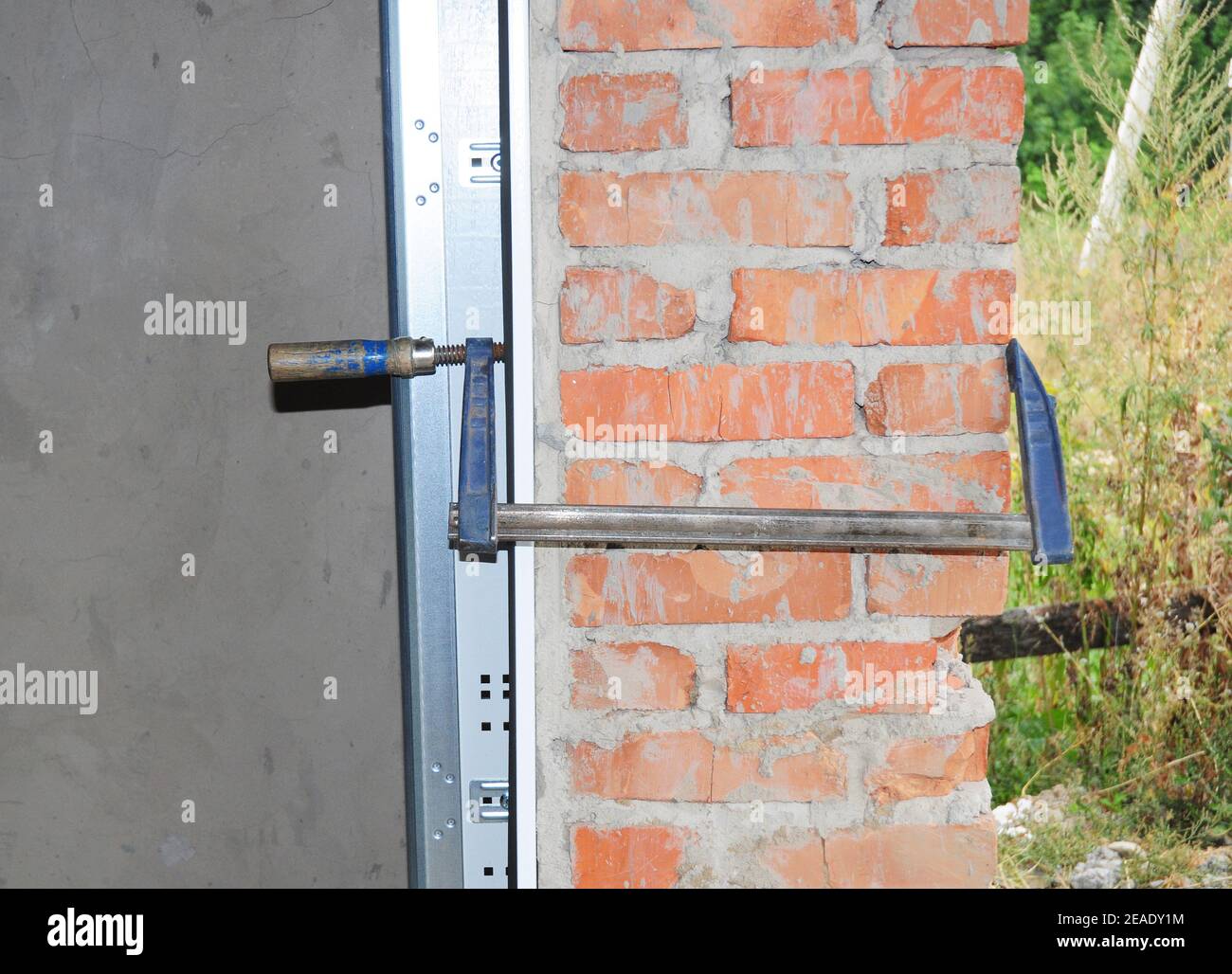 Garagentorinstallation, Montage des Türrahmens an den Türsturz mit einem Arbeitswerkzeug. Stockfoto