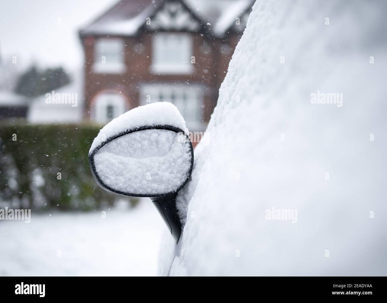Autospiegel geparkt auf Fahrt schneite in Haufen von Schnee Angesiedelt auf Top-Haus im Hintergrund auf Wohnstraße Stockfoto