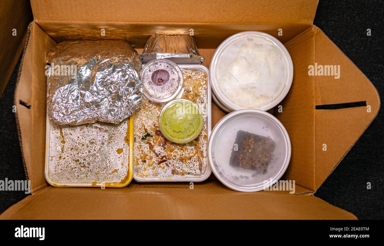 Draufsicht auf Lebensmittel zum Mitnehmen in Kunststoffbehältern und Aluminiumfolie in einem Karton. Stockfoto