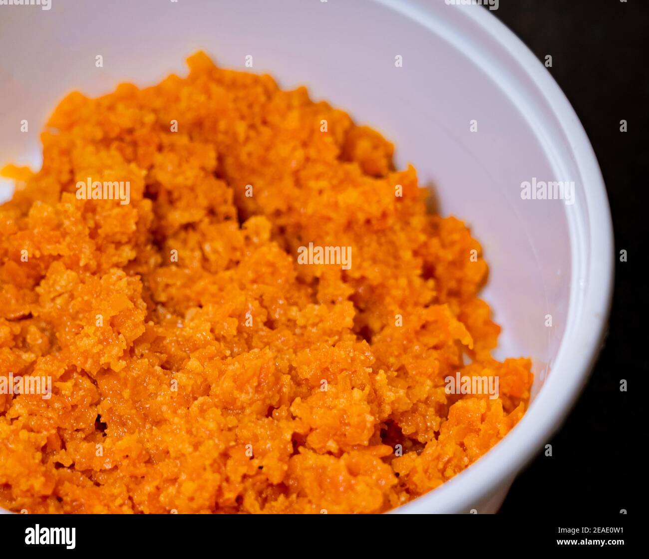 Nahaufnahme von Karotte Halwa oder Gajar ka halwa in einer weißen Takeout-Box auf schwarzem Hintergrund. Stockfoto