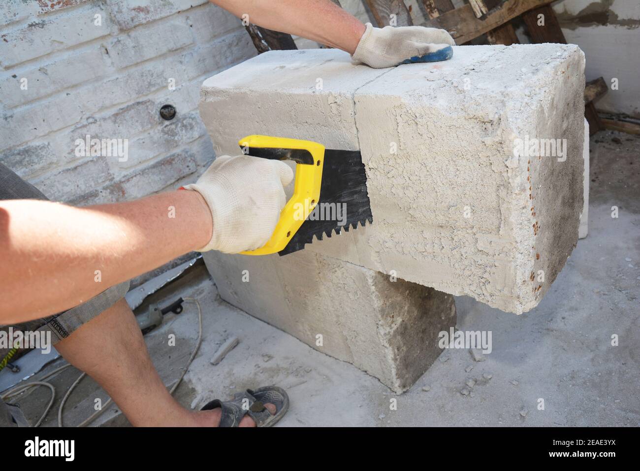 Ein Bauunternehmer schneidet autoklaviertes Porenbeton-Block, Gasbeton mit einer Handsäge auf einer Baustelle. Stockfoto