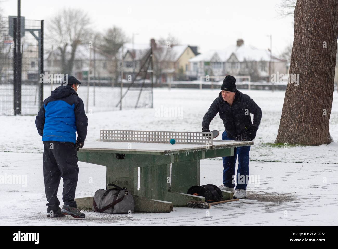 Zwei Leute spielen Tischtennis im Schnee im Priory Park in Southend on Sea, Essex, Großbritannien, mit Schnee von Storm Darcy. Eiskalt. Winter Stockfoto