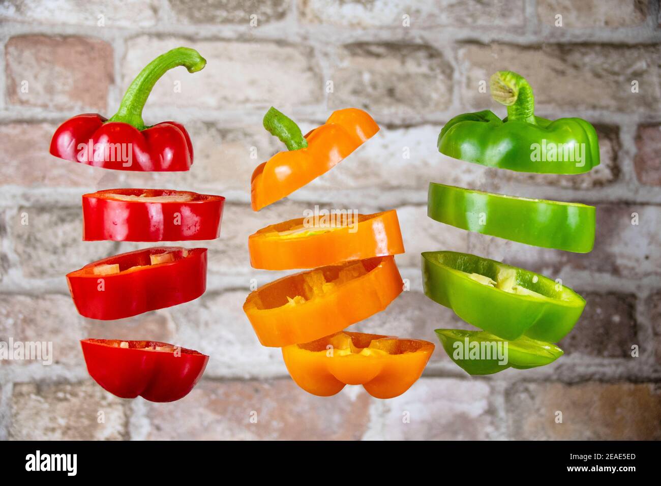 Sliced Bell Peppers Kapsicums schwimmend gegen Ziegelwand Stockfoto