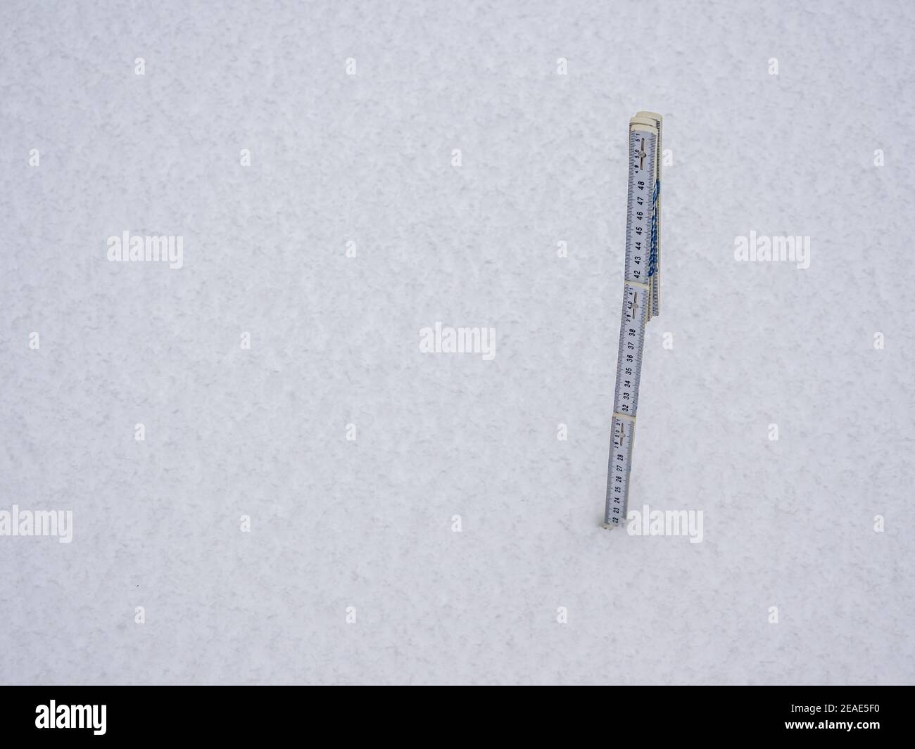 Messen Sie die Schneehöhe mit einer Klappregel Stockfoto